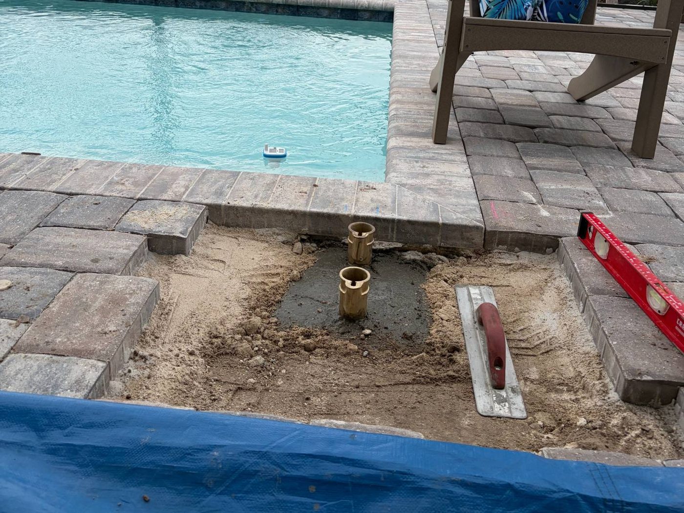 Brass anchor sockets set level in the cured concrete footing beneath the paver deck