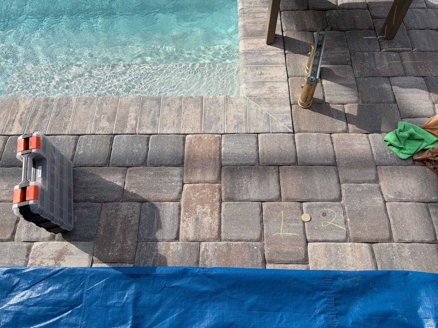 Pavers beside the pool steps marked with chalk where each leg of the handrail will go